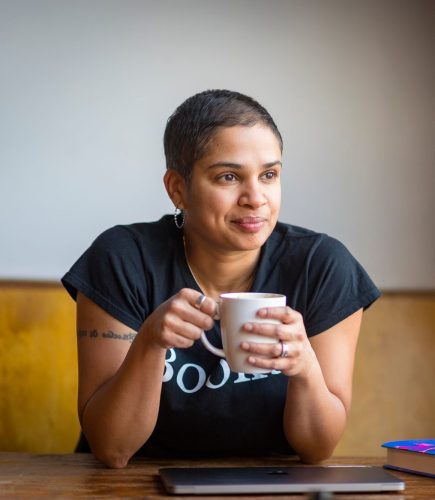 Queer author Tanya boteju, a woman with short dark hair, brown eyes, and medium skin tone.